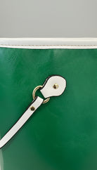 Green handbag with a white strap and gold clasp on a blurred background