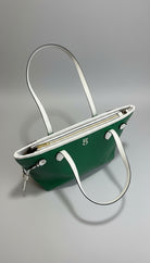 Green handbag with a white strap on a wooden surface