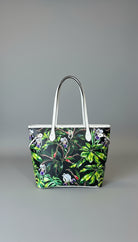 Tropical leaf patterned bag on a marble surface with a blurred background