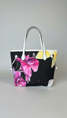 Handbag with floral design on a marble surface, with clothing and decor in the background.